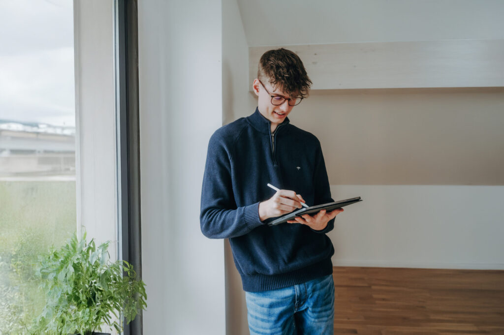 Erstellung eines Marketingkonzepts von der Kontraste Agentur, Person steht am Fenster und schreibt auf Tablet