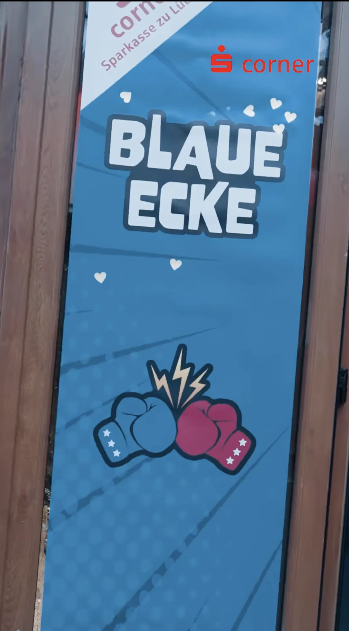 Ein blaues Banner mit der Aufschrift 'BLAUE ECKE', zwei Boxhandschuhen (blau und rot) und dem Sparkasse-Logo.