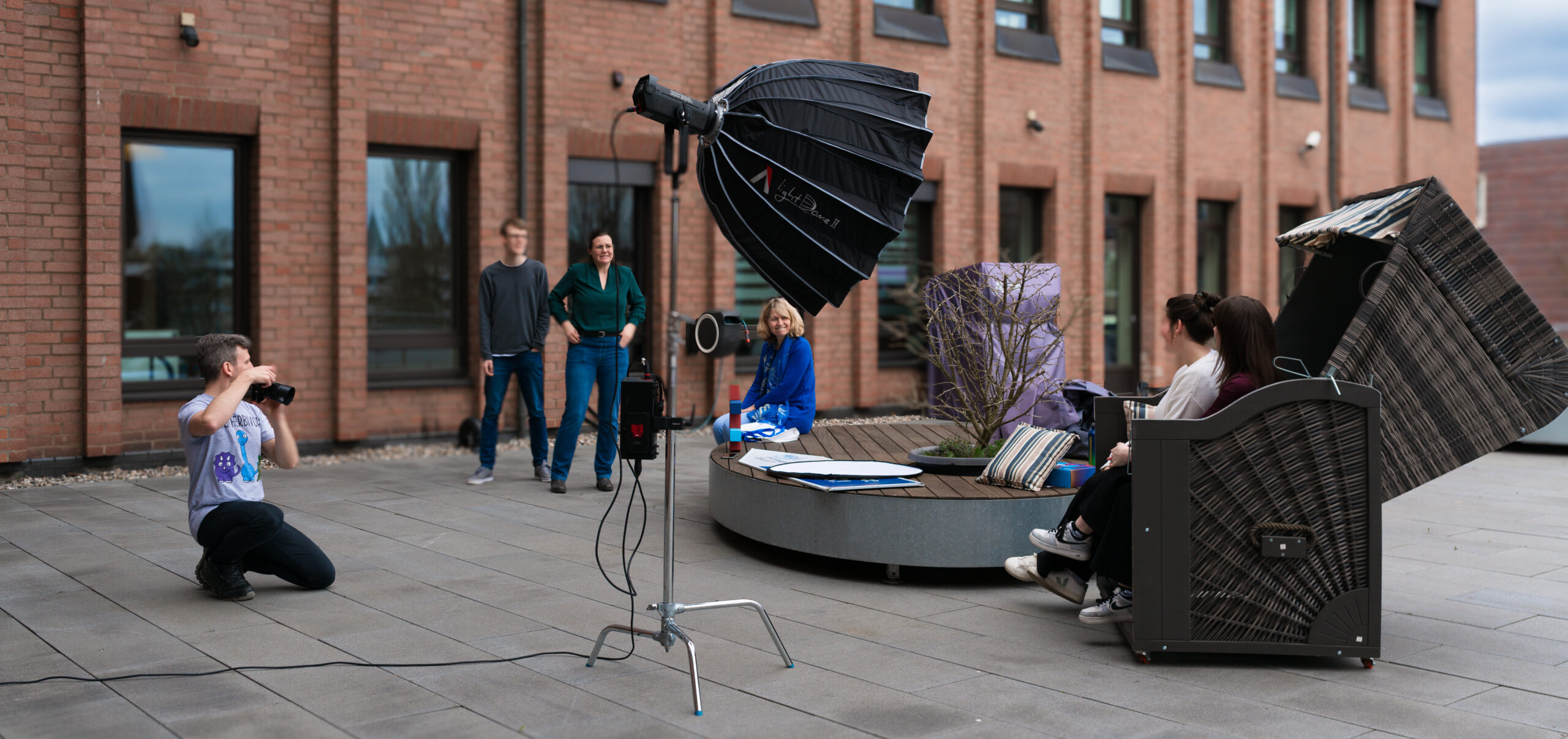 Ein professionelles Fotoshooting für die IHK auf einer Außenterrasse mit Fotograf, Models, Beleuchtung und Requisiten.