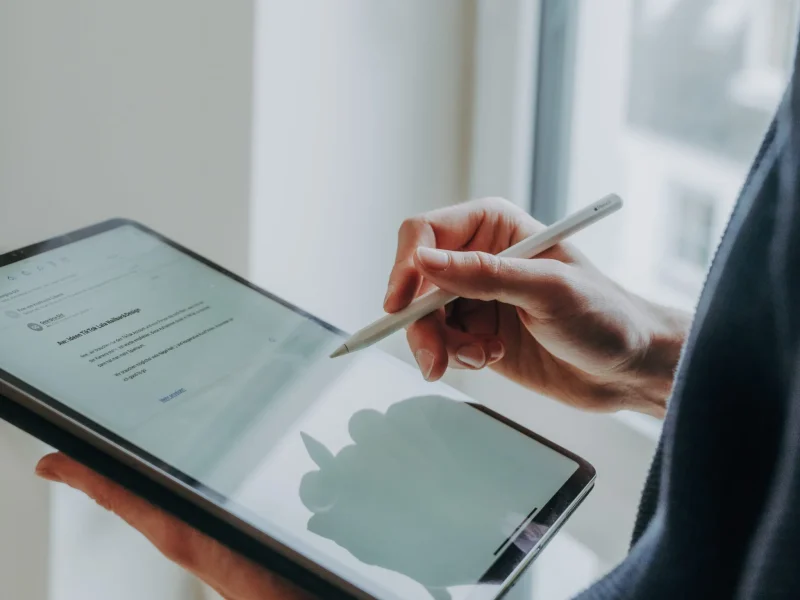 Eine Person hält ein Tablet und schreibt mit einem Apple Pencil auf dem Bildschirm, der einen Entwurf für TikTok-Inhalte zeigt.