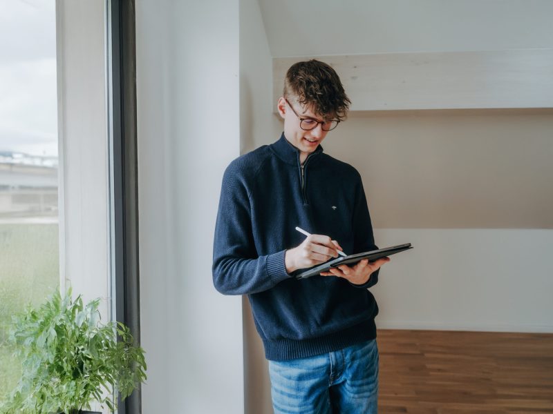 Erstellung eines Marketingkonzepts von der Kontraste Agentur, Person steht am Fenster und schreibt auf Tablet